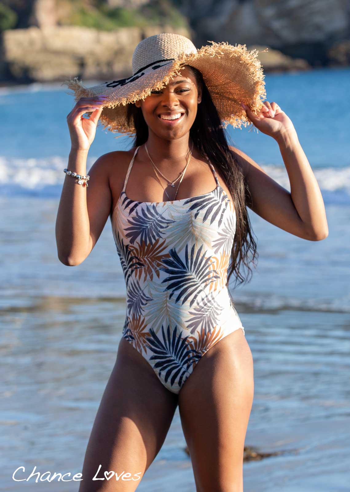 Smiling teen girl wearing a beach hat and a beautiful one piece swimsuit with tropical palm print