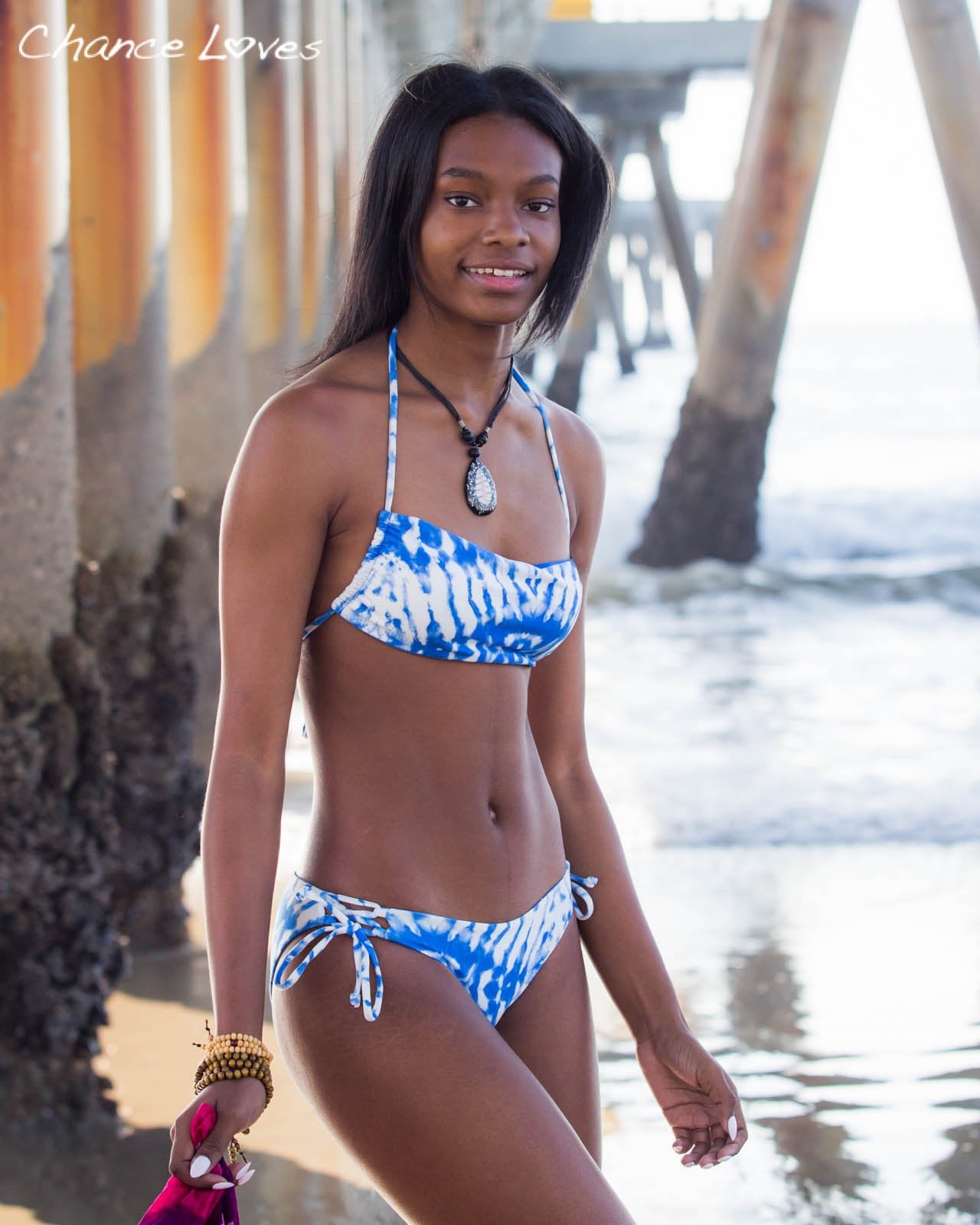 A drawstring blue and white Bando Bikini top and matching full coverage swim bottoms in Venice worn by a beautiful young woman
