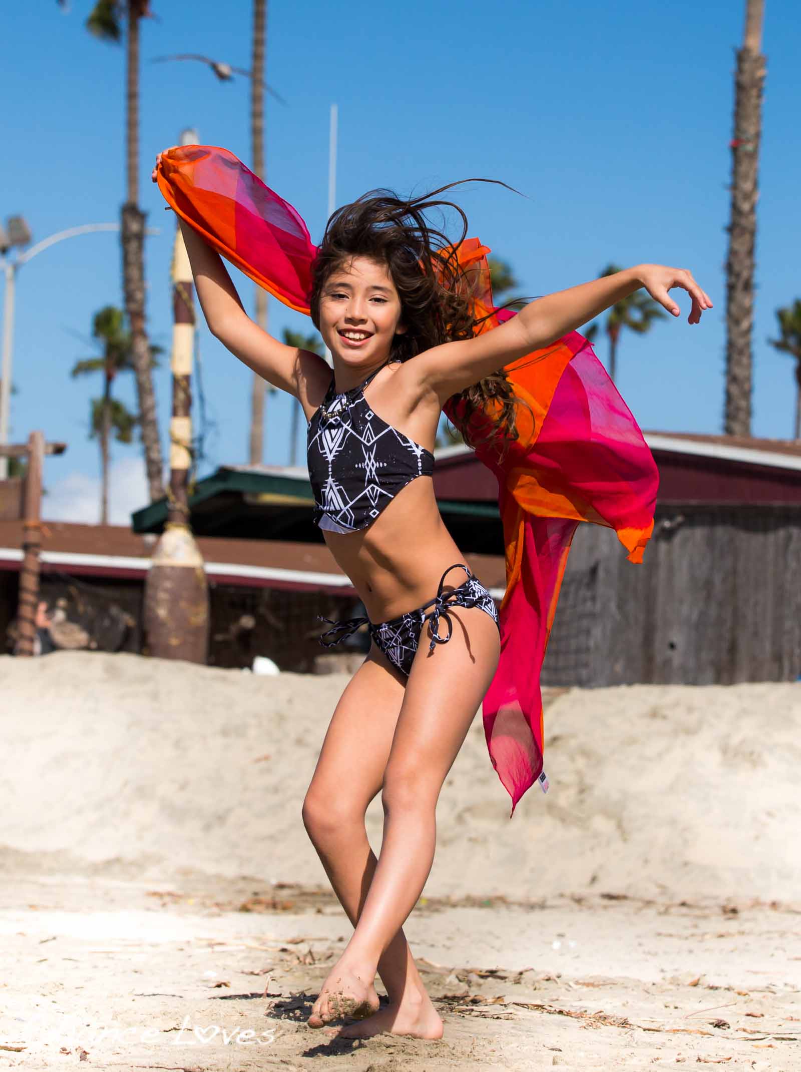 Dancing Beach girl wearing a cute Chance Loves Swim Bikini, styled with an orange pink shawl