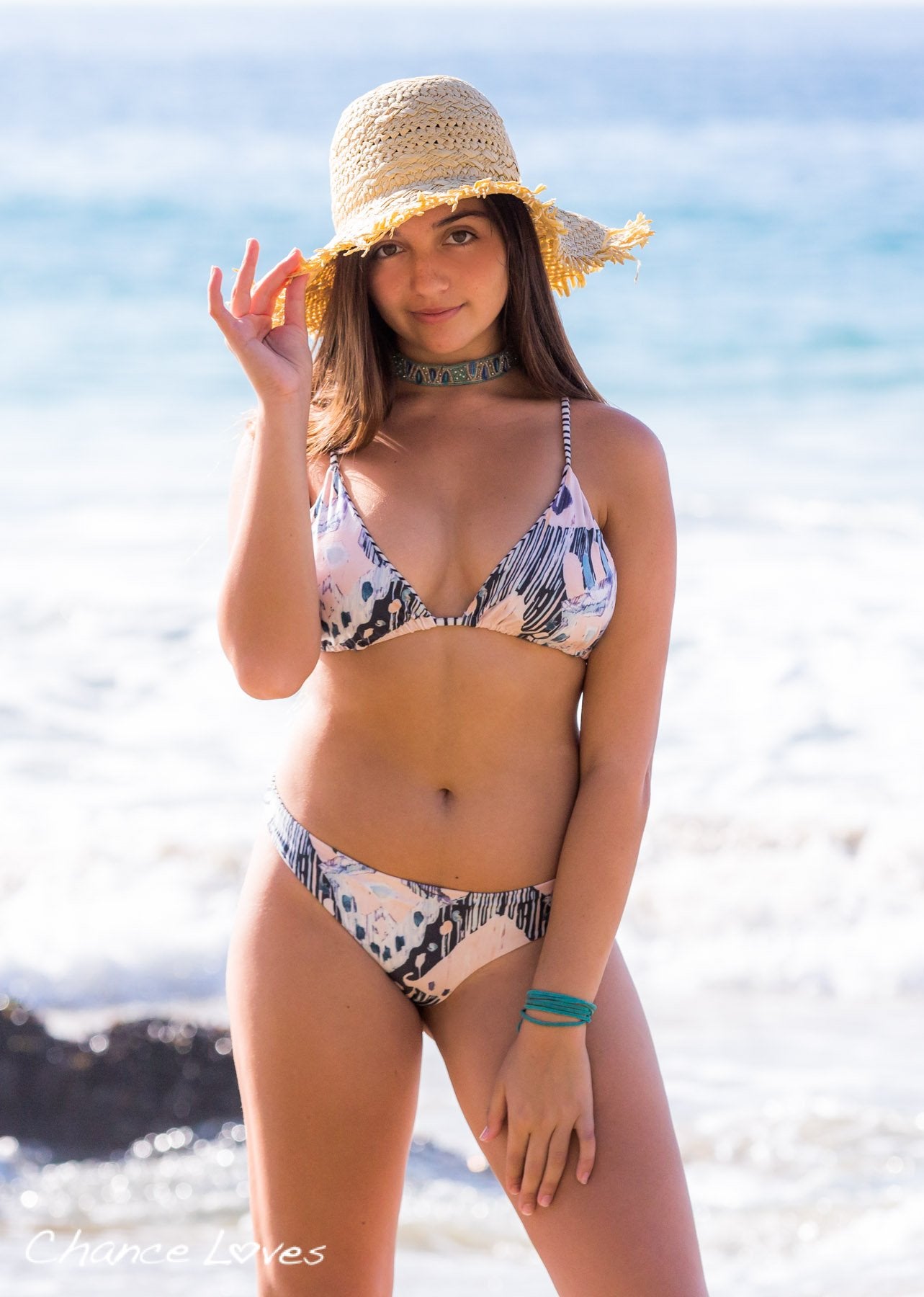 Beautiful young woman at the beach in front of amazing blue water, wearing an amazing reversible Bikini.